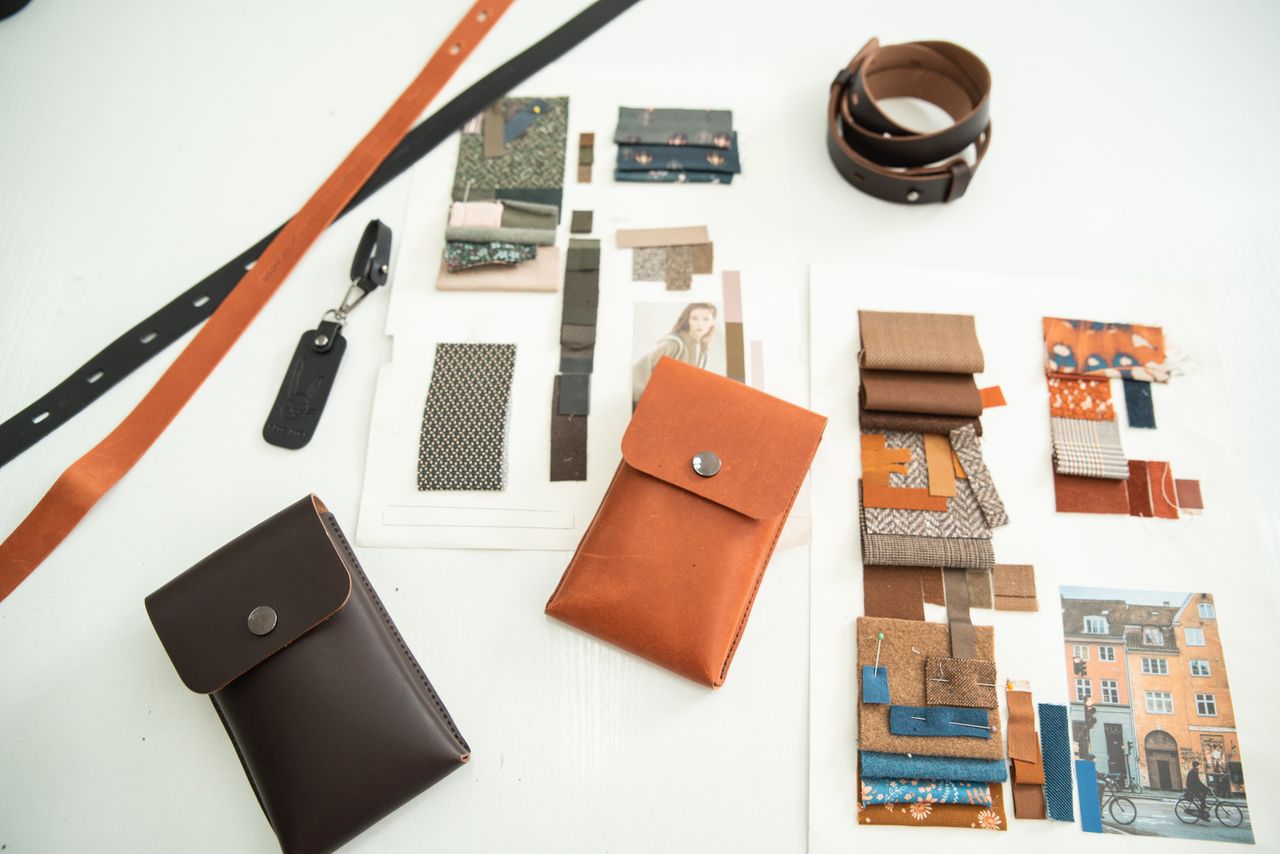 A modern workspace showcasing leather accessories and fabric moodboards for fashion design inspiration.
